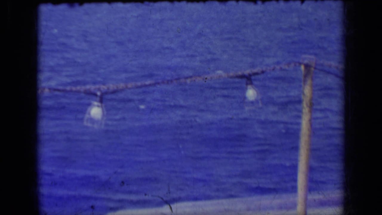 Blue water with distant pale mountains and rope lights in the foreground.
