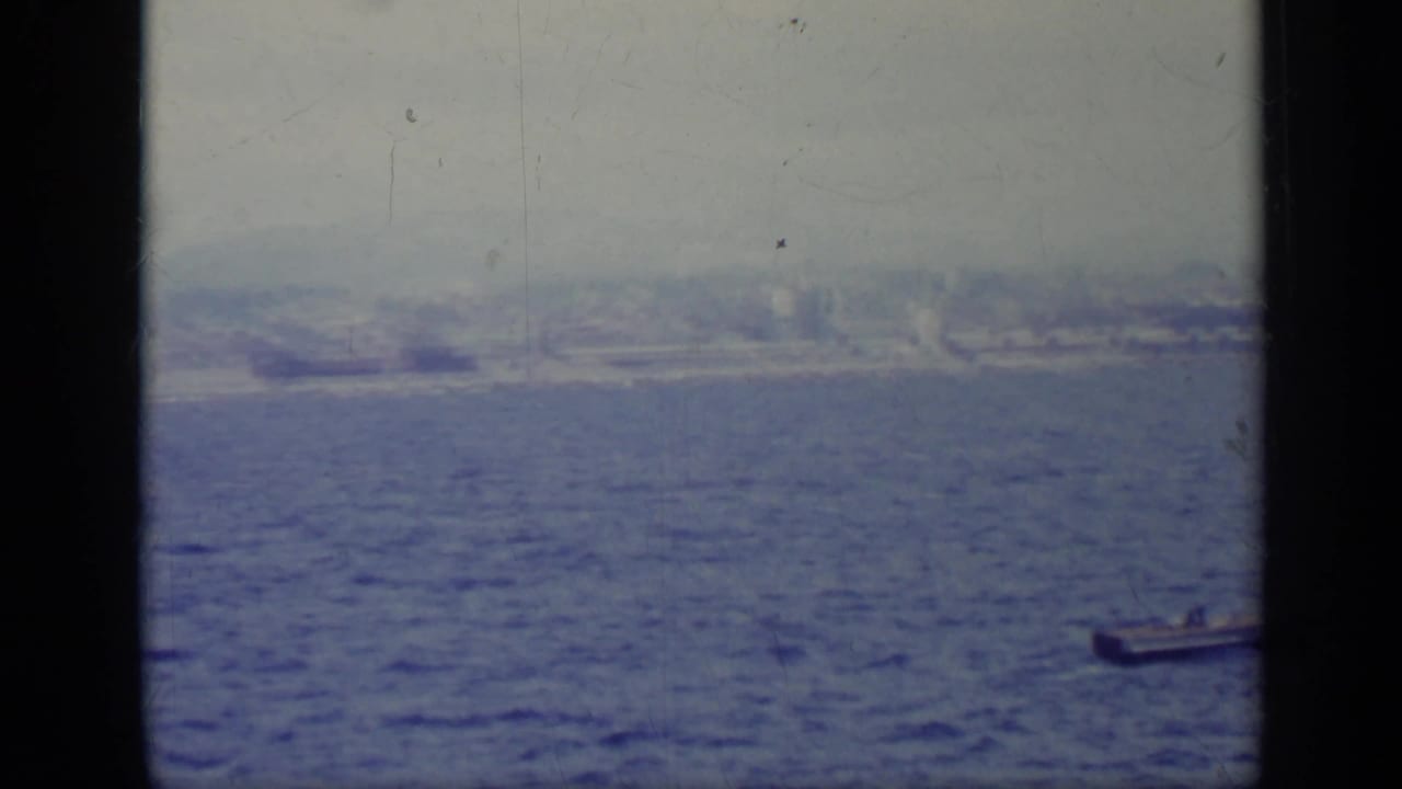 Hazy shoreline seen across open water from a vessel.