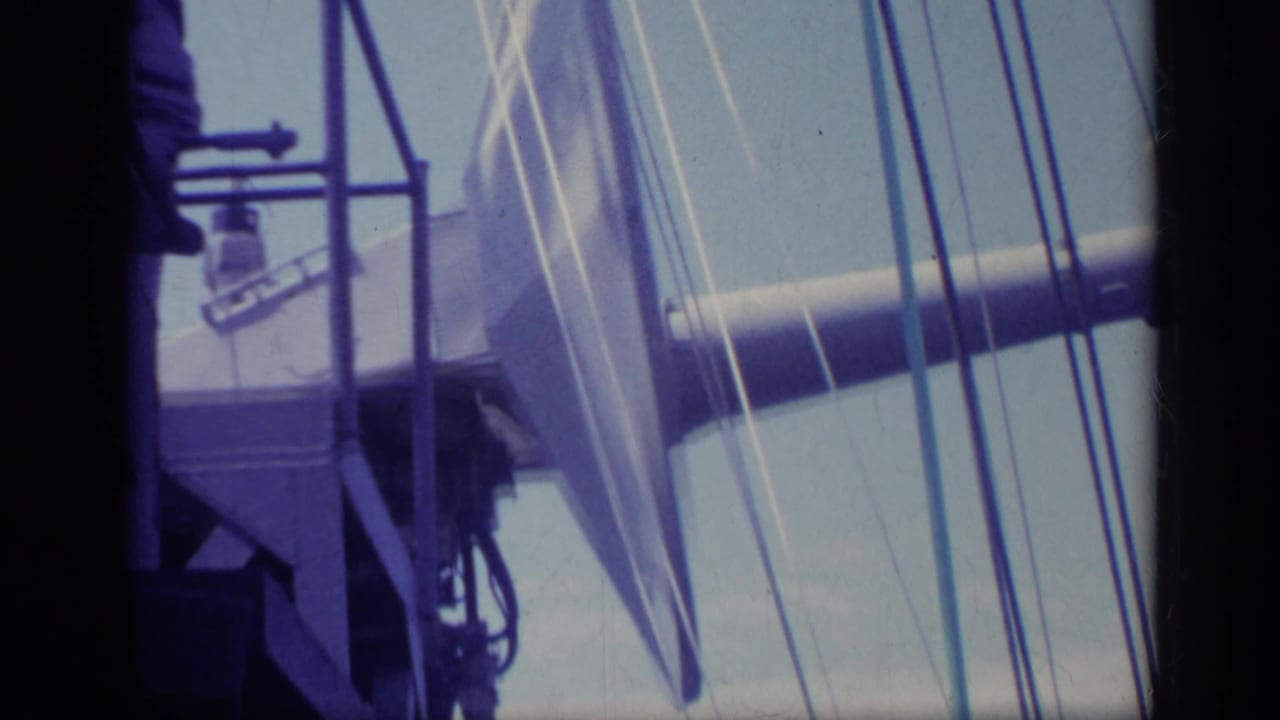 Ship railings and rigging beside a large angled deck structure.