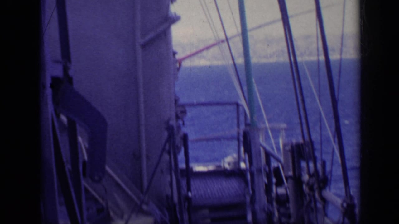 1962 8mm footage from Italy shows a freighter deck with railings, rigging, and open sea ahead.
