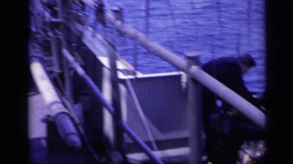 A crew member appears near freighter deck equipment and railings, with open ocean visible beyond.