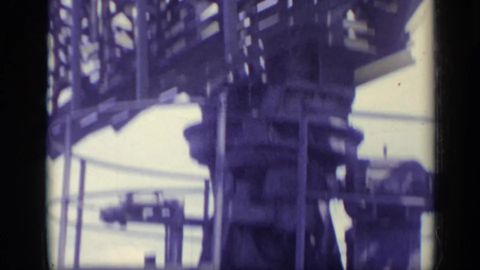 1962 Italy frame showing a large gray lattice structure and waterfront railings from a moving boat perspective.