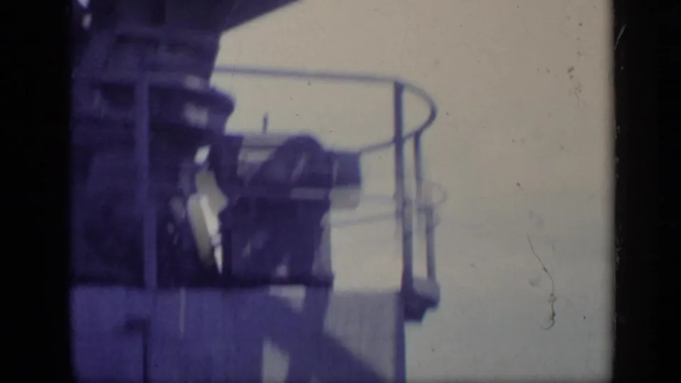 Onboard 1962 Italy frame with deck equipment, curved railing, and hazy light beyond the ship structure.