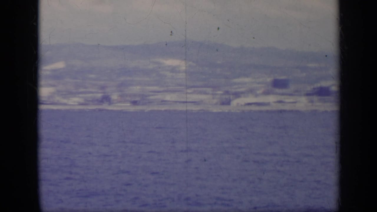 Distant shoreline city across blue water under a hazy sky.