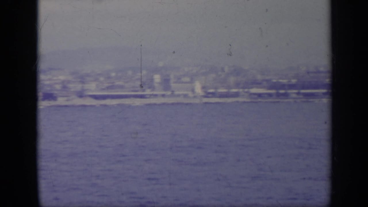 Distant coastal city seen across water through dark vertical framing bars.