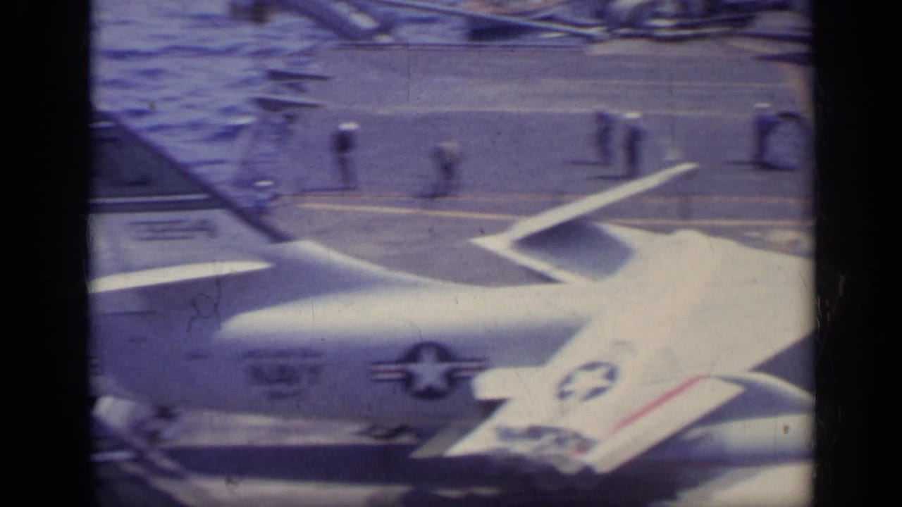 U.S. military aircraft on an aircraft carrier deck with film gate borders.