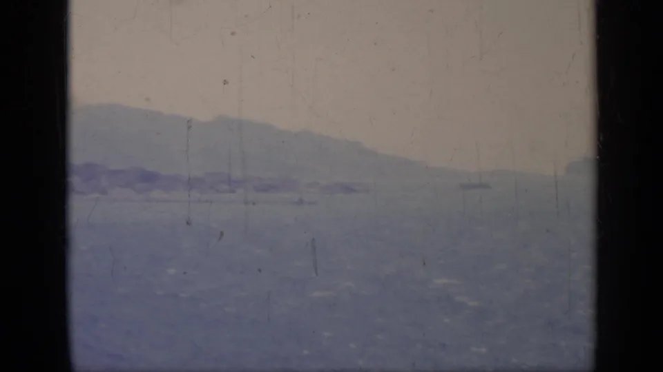 1962 Italy 8mm frame showing a hazy coastal horizon and distant landform from a seaside vantage point.