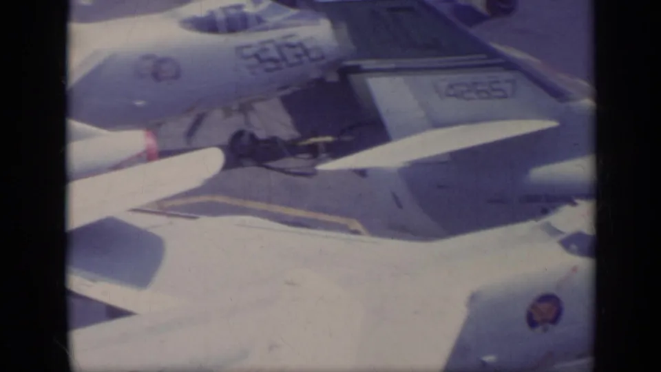 1962 Italy-associated 8mm frame of parked U.S. Navy aircraft on a carrier deck, with the 506 nose marking and tail number 142657 visible.