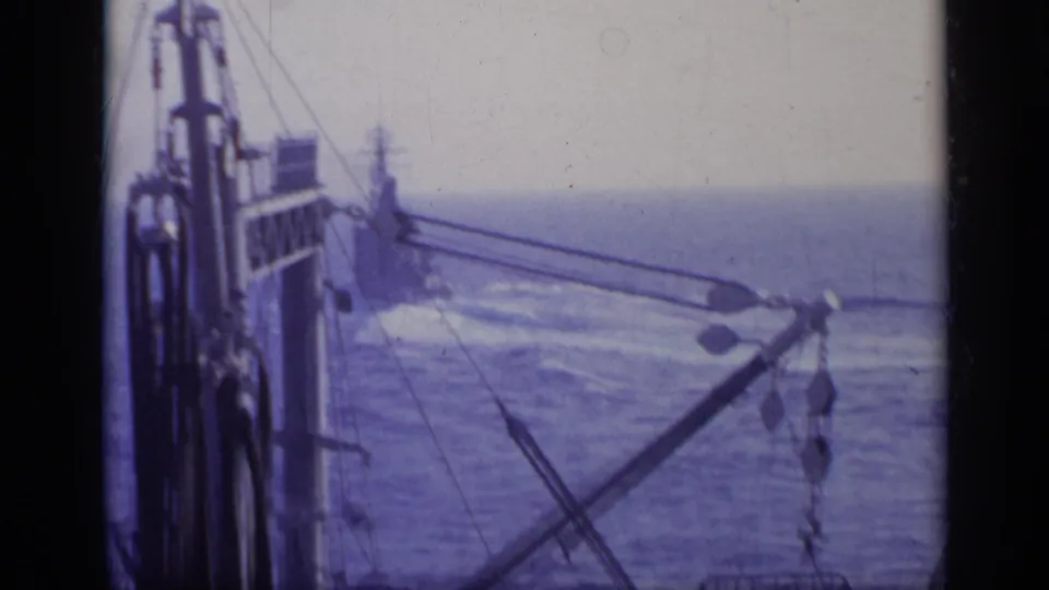 1962 Italy frame showing crane arms, hanging lines, and ship structure during a naval operation at sea.