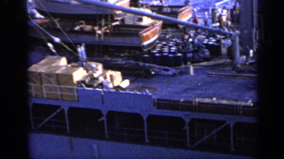 1962 Italy 8mm frame showing stacked cargo or containers, bundled deck items, railings, and part of a crane or boom structure.