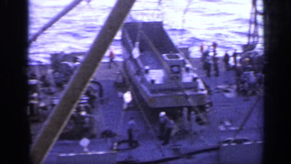 1962 ship deck scene with several crew figures near a secured small boat or cargo craft, ropes, railings, and open water.