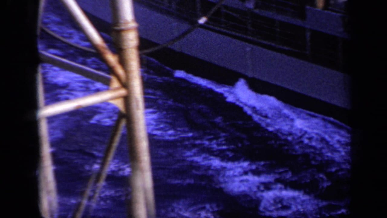 Ship rail and metal supports above dark blue choppy water.
