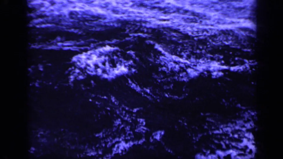1962 Italy 8mm frame focused on restless blue-black water with streaks of white foam.