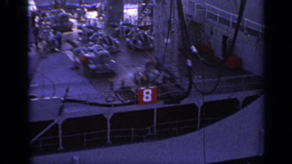 1962 Italy 8mm frame showing a ship deck with equipment, railings, small visible figures, and a red number 8 sign.