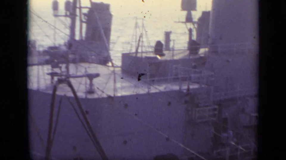 1962 Italy 8mm frame showing close views of a naval vessel's deck structures, railings, and equipment at sea.