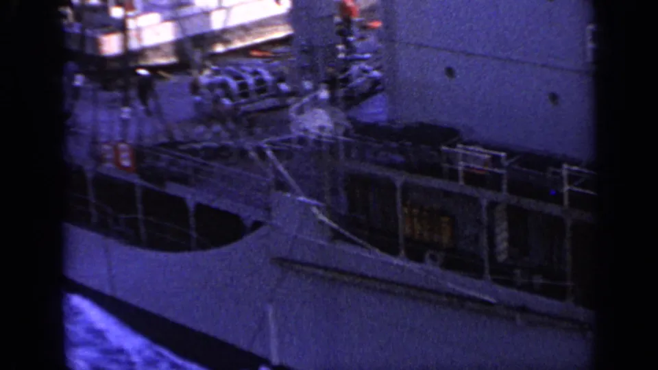 1962 Italy 8mm frame showing the side of a large passenger ship with rigging, railings, deck equipment, and blue sea below.