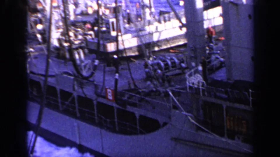 1962 Italy 8mm frame of a large working vessel at sea, with rigging, deck machinery, railings, and wake visible.
