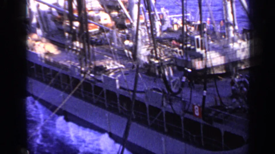 Large industrial ship underway in 1962 Italy footage, showing deck gear, vertical rigging, railings, and water at the hull.