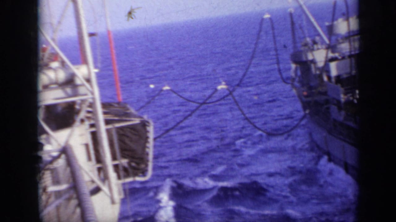Ship deck and railings beside open ocean with another vessel close alongside.
