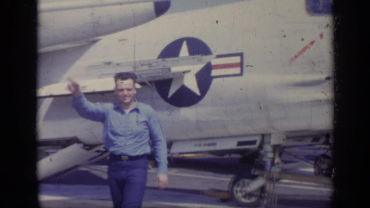 Man waves while standing near the fuselage of a U.S. military jet.