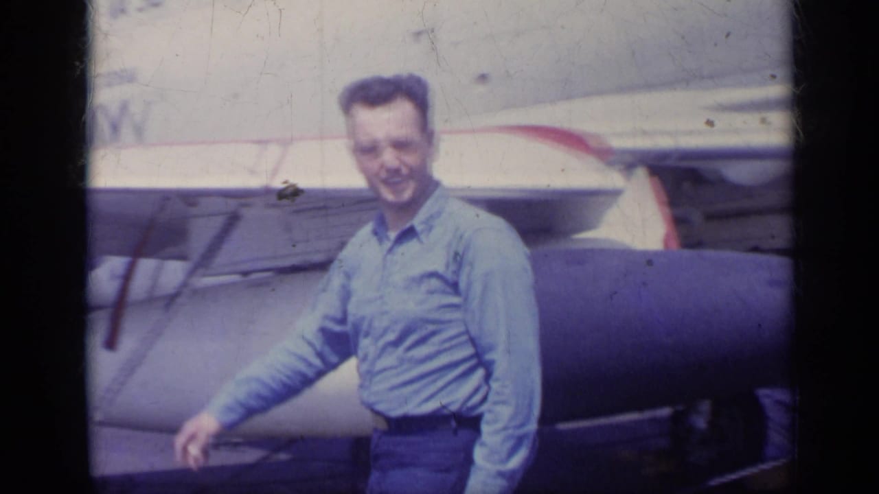 In 1962 Italy footage, a man smiles on a U.S. Navy carrier deck with aircraft or missile hardware behind him.