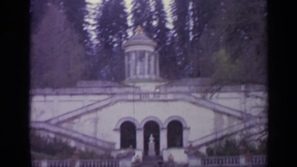 Faded 8mm view of a 1962 Italian stair monument with a small columned pavilion, arched terrace and surrounding trees.