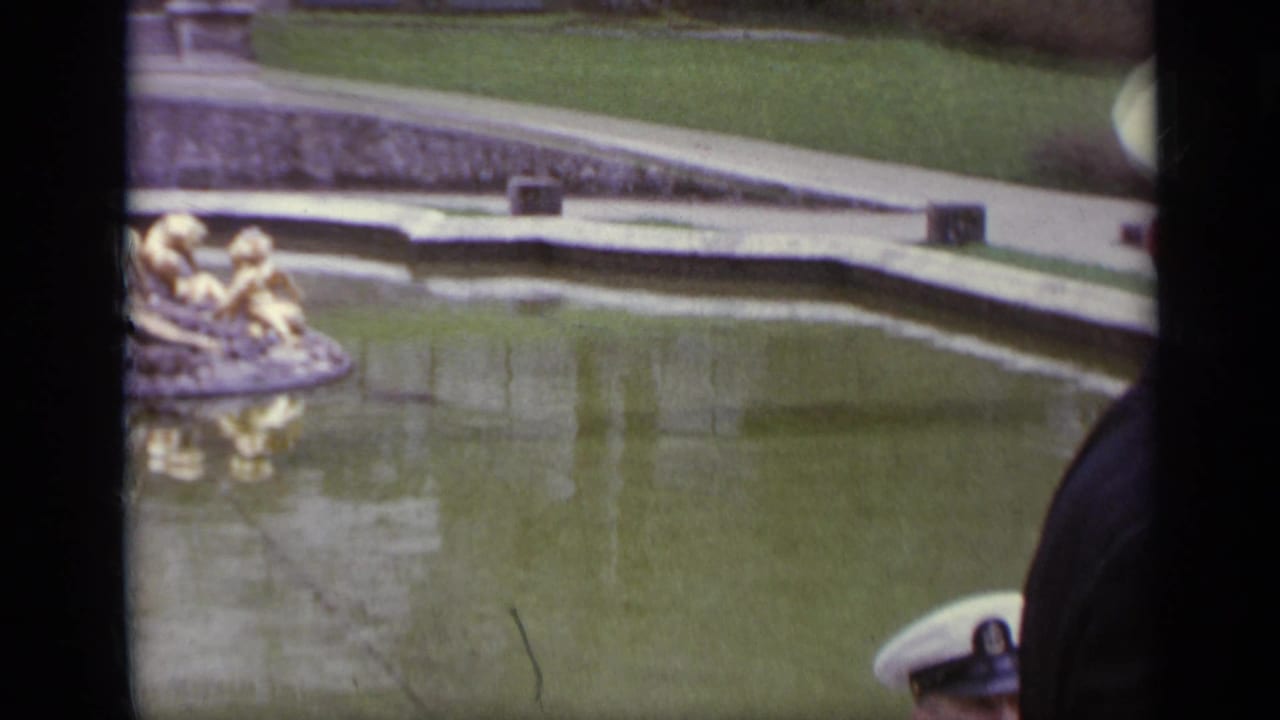 Reflective pool with gilded fountain sculpture and a white military cap at the edge.