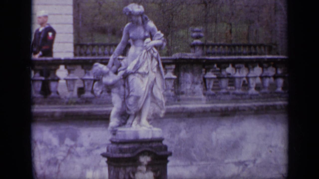Classical statue with a child beside stone balustrades and a sailor at the left edge.