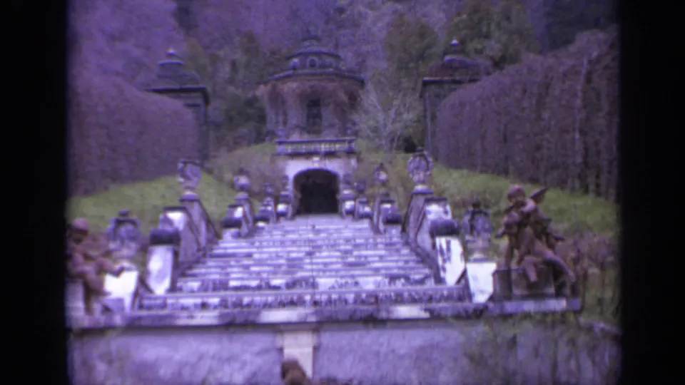 The 1962 home-movie view centers on the garden staircase, with stone balustrades, lantern posts, hedges, and figures along the sides.