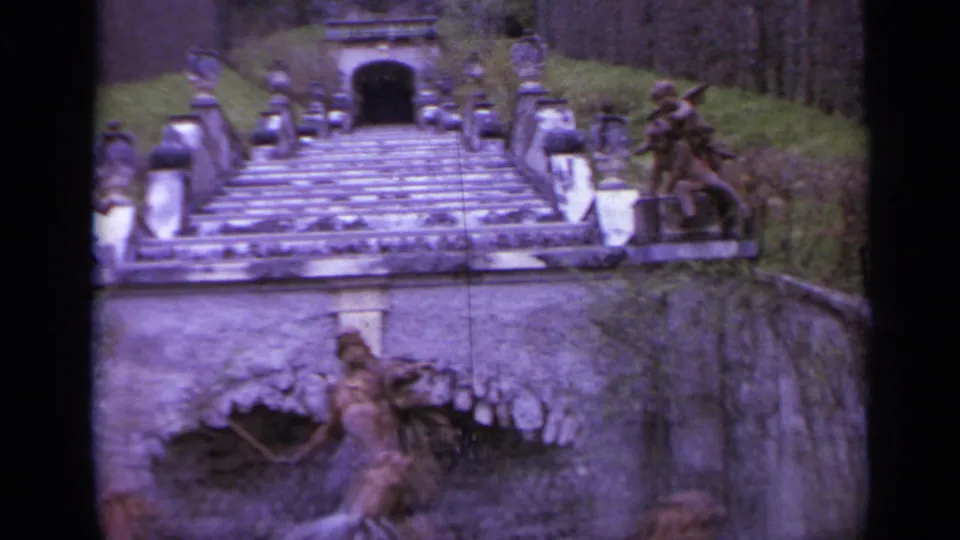 A lower view shows flowing water at a stone basin below the staircase, with lantern posts, hedges, and classical figures nearby.