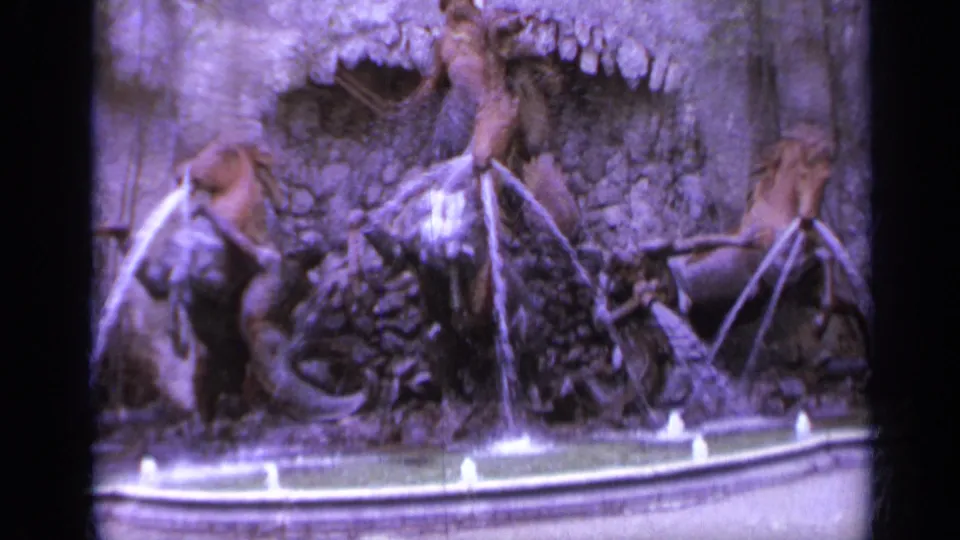 1962 Italy 8mm frame focused on horse and figure sculptures sending water into an ornate fountain basin.