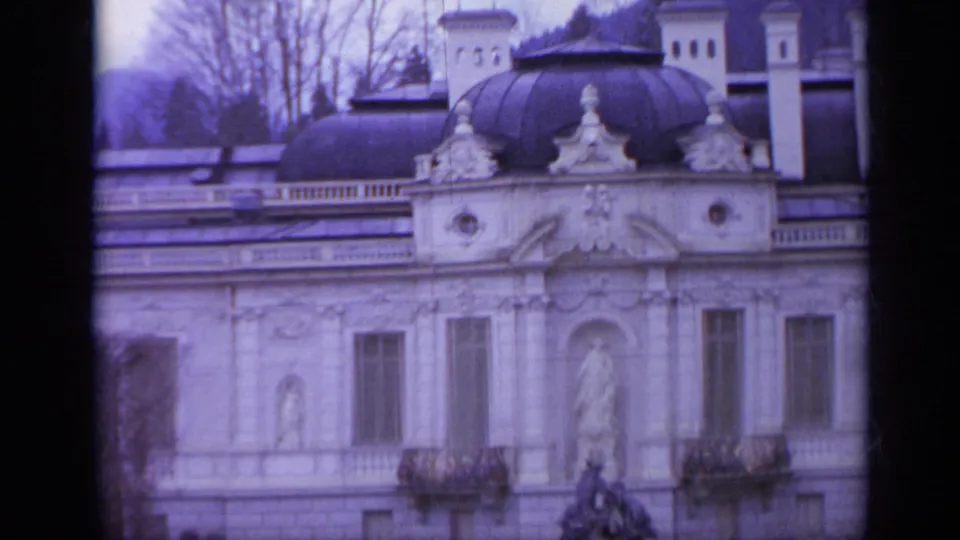 1962 Italy 8mm frame showing decorative roofline sculpture, tall windows, balconies, and a central statue niche on an ornate facade.