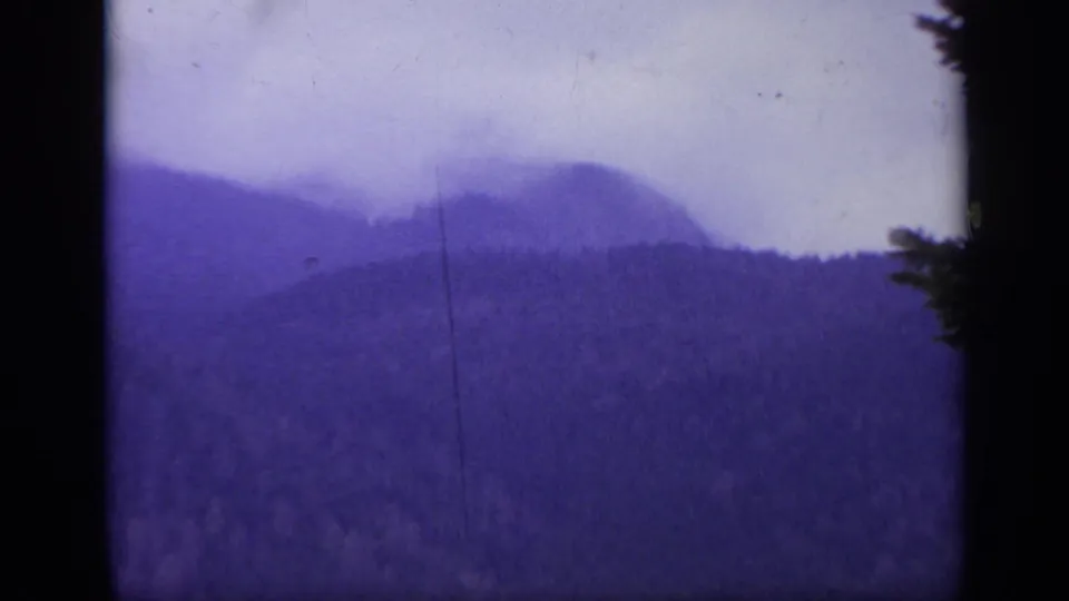 1962 Italy 8mm frame with layered mountain slopes, misty sky, dark gate borders, and visible physical-film wear.