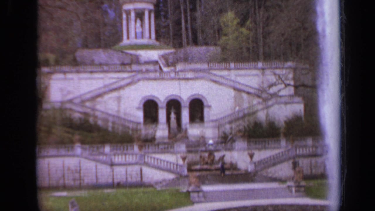 Formal garden staircase with arched openings and a small monument above.
