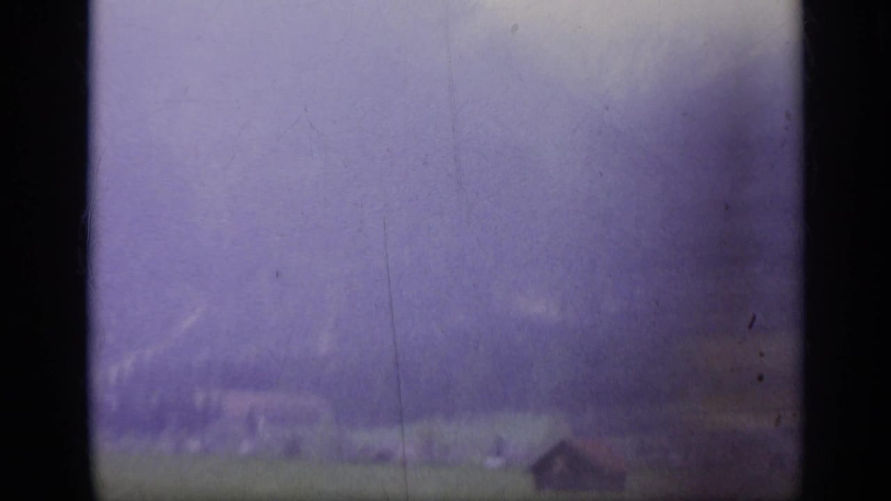 Foggy mountain valley seen through dark film gate edges.