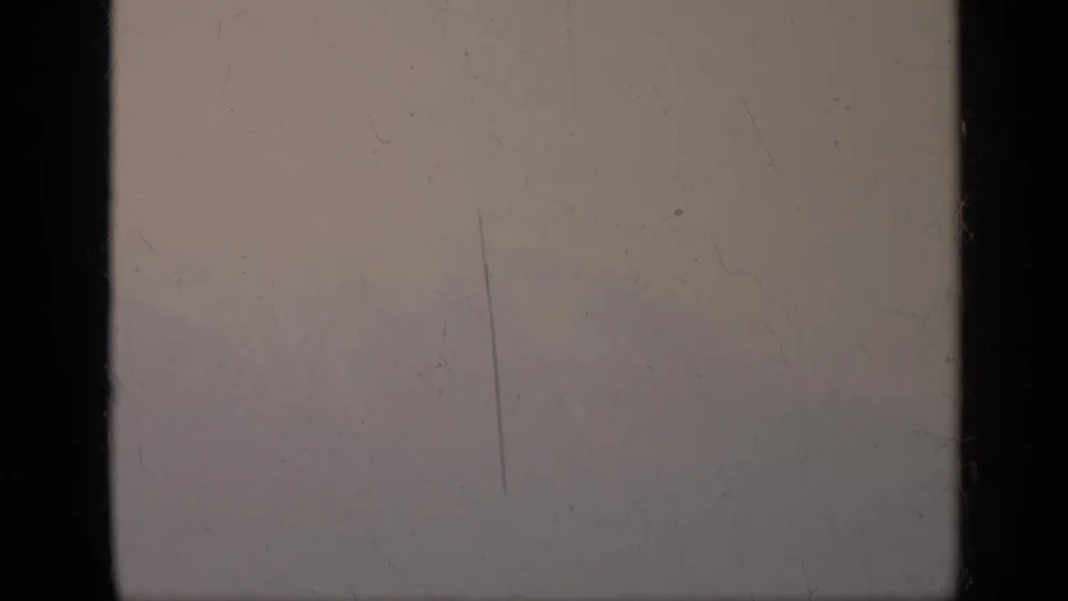 Late frame from the 1962 Italy mountain clip, showing a nearly washed-out fog view divided by a dark window bar and marked by 8mm wear.