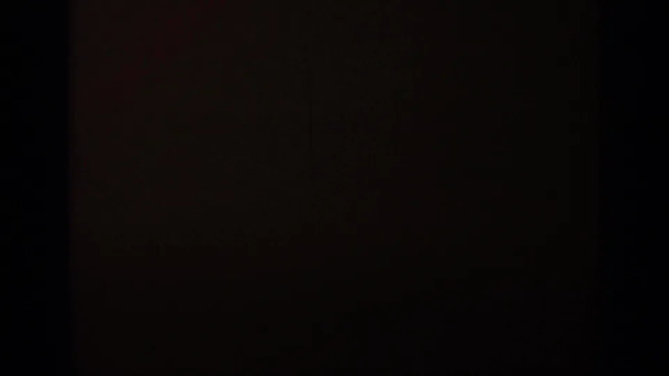 Opening 8mm frame from the 1962 Italy clip, largely obscured by dark exposure with a small glimpse of pale mountain scenery.