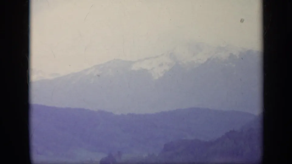 1962 Italy 8mm frame showing snow-capped Alpine peaks and distant ridgelines in soft exposure and muted color.