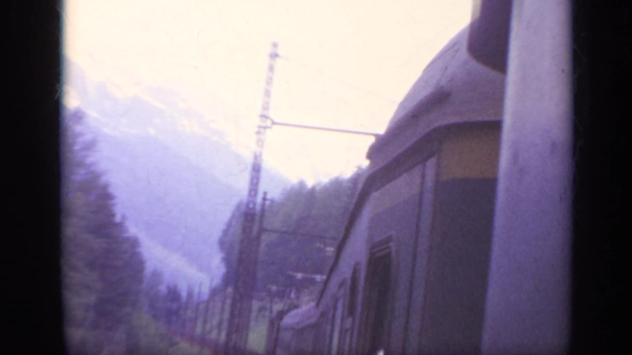 Train car and overhead electrical pole passing through a hazy mountain valley.