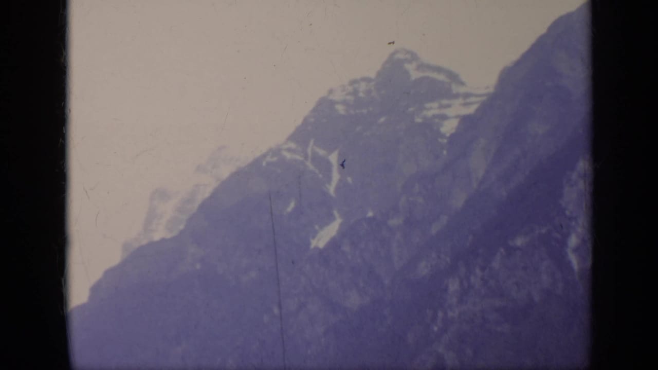 Snow-capped mountain peaks seen through a dark 8mm frame edge.