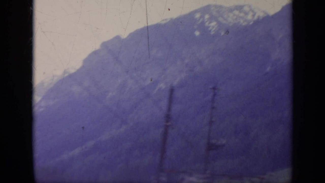 Snowy mountain slope seen through dark vertical frame edges.