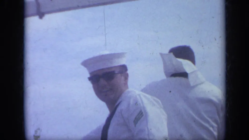 Two sailors in white uniforms and caps appear in a 1962 Italy 8mm frame, with one face turned toward the camera.