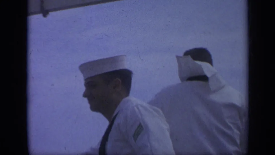 1962 Italy shipboard frame with a side view of one sailor and another sailor seen from behind against the sky.