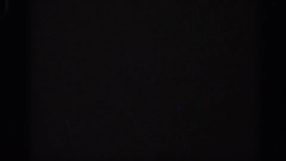 Underexposed 1962 Italian 8mm frame with faint film texture and a small blue light mark near the lower right.