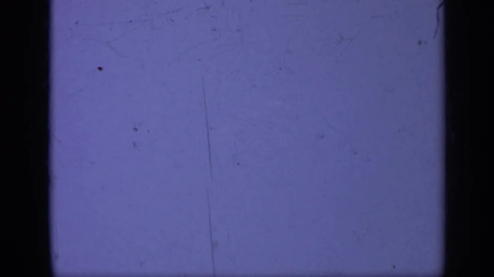 Faded 1962 8mm frame from the Italy-associated clip, mostly blank with purple color shift, scratches, dust, and dark film edges.
