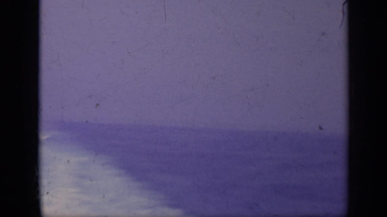 Hazy ocean horizon with a pale patch of water and dark film borders.