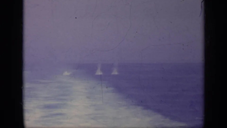 1962 Italy-associated 8mm sea view with distant white plumes that appear to be whale spouts against a hazy horizon.