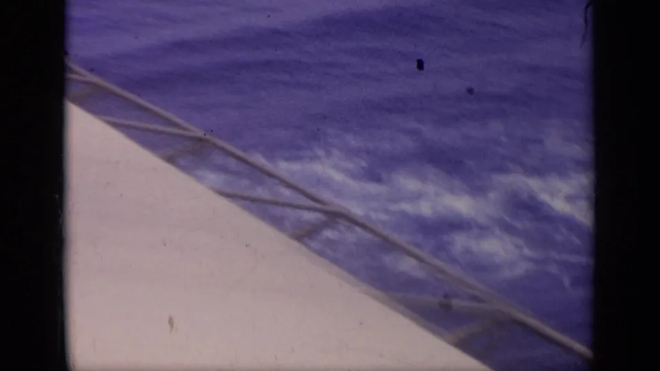 The camera turns toward the carrier deck edge and surrounding sea, showing water texture and deck railing in the 1962 Italy clip.