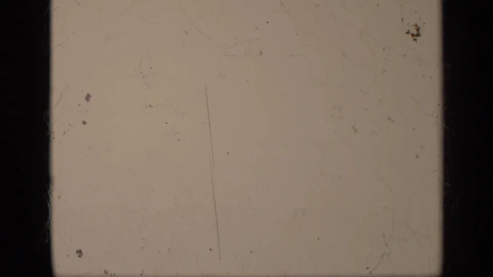 A nearly blank faded 8mm frame from the 1962 Italy clip shows pale exposure, scratches, dust, and dark vertical gate borders.