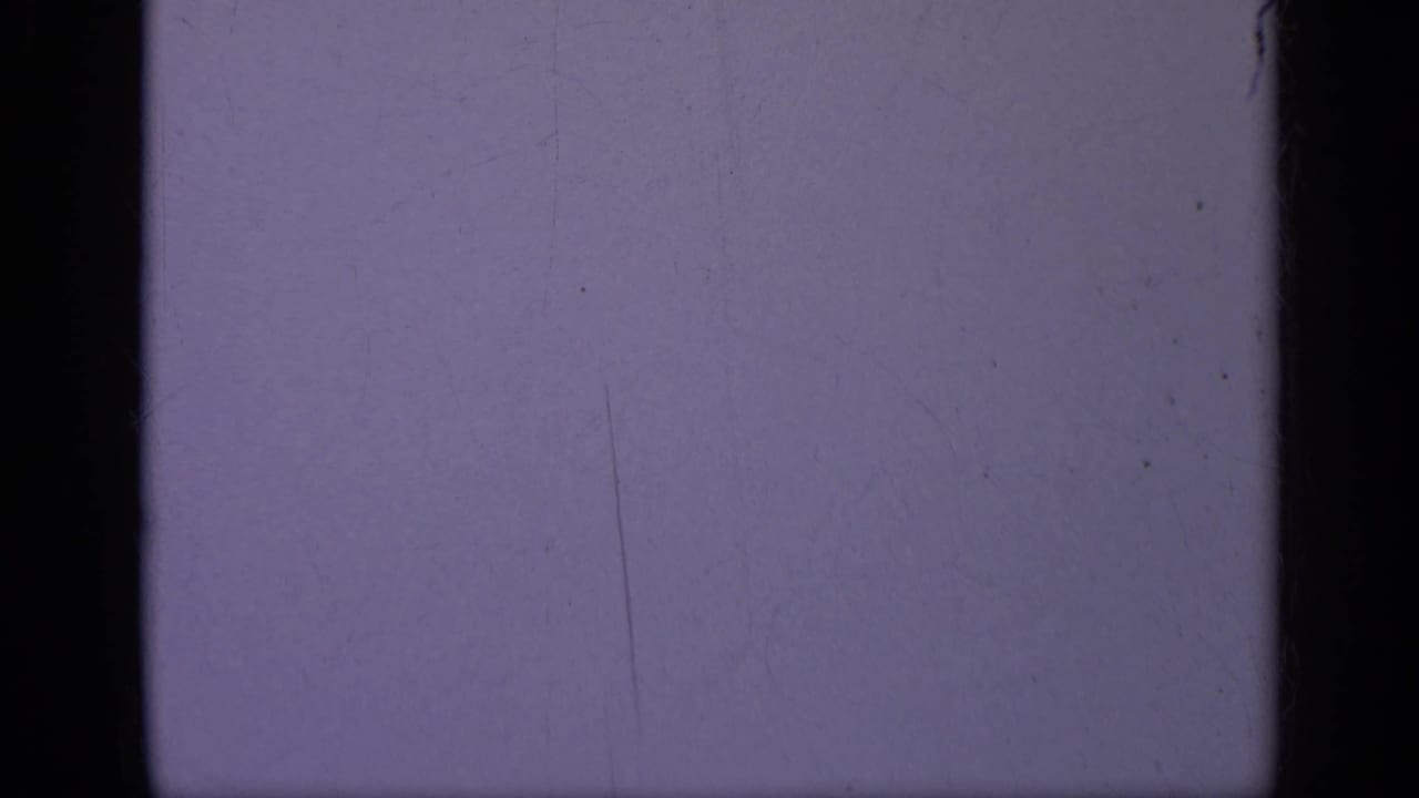 1962 Italy 8mm frame with a cool blue-purple exposure field, black gate edges, dust specks, and visible film wear.